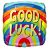 A square foil balloon with rounded corners, featuring a vibrant rainbow-striped background and the words 'GOOD LUCK!' in large gold letters with black outlines.